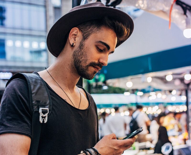 Mann mit Hut schaut auf Handy