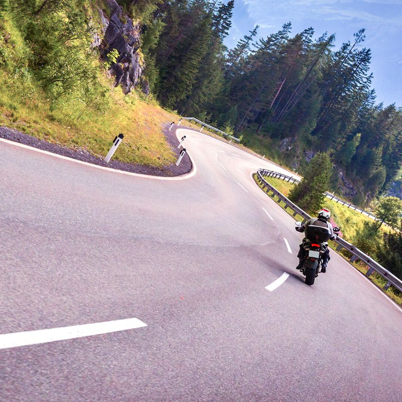 Motorradfahrer auf kurviger Strasse in den Alpen
