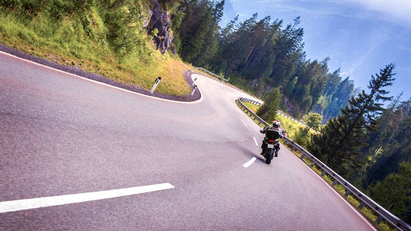 Motorradfahrer auf kurviger Strasse in den Alpen