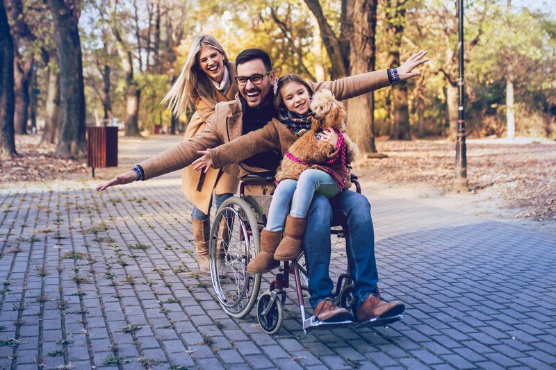 Mann im Rollstuhl und seine Familie haben Spaß