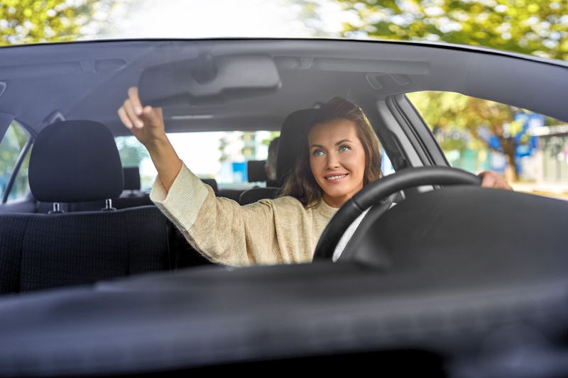 Frau stellt Rückspiegel im Auto ein