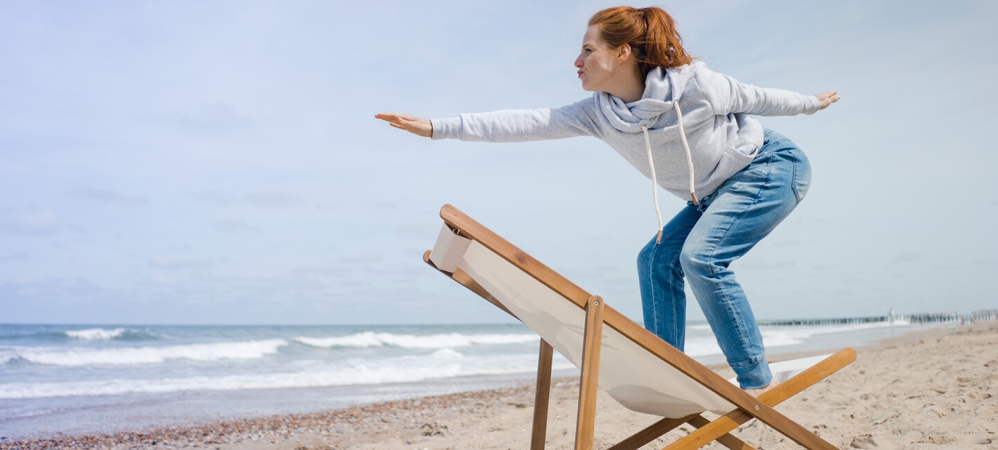 Frau surft am Strand auf Klappliegestuhl