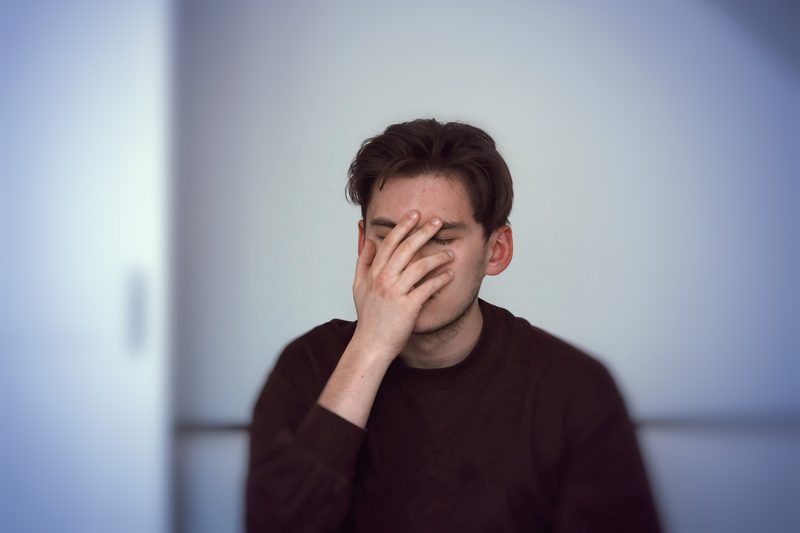 Mann verdeckt sein Gesicht mit den Händen