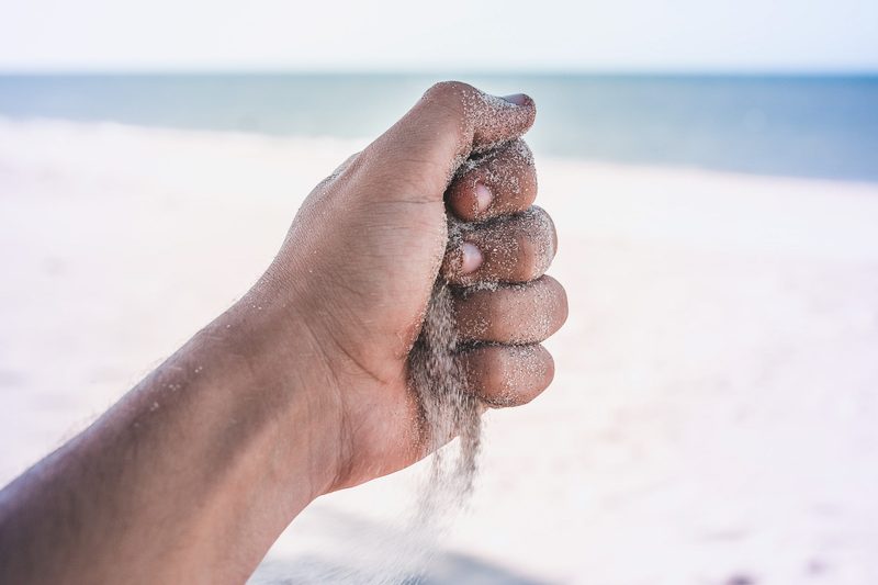 Sandstrand fließt durch eine Hand