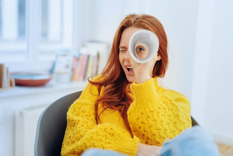 Frau schaut durch Papierröhre