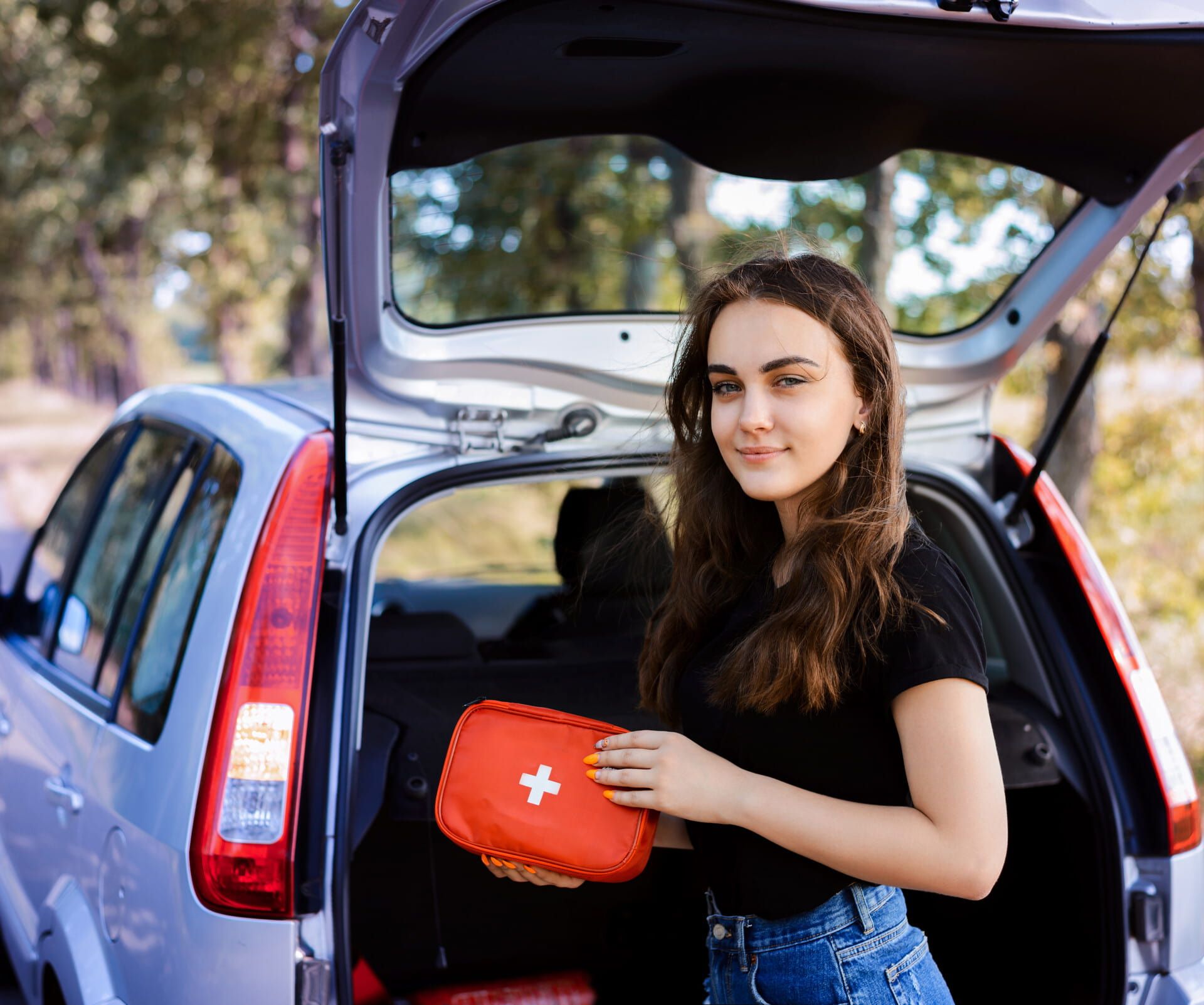 Frau mit Erste-Hilfe-Kasten am Auto