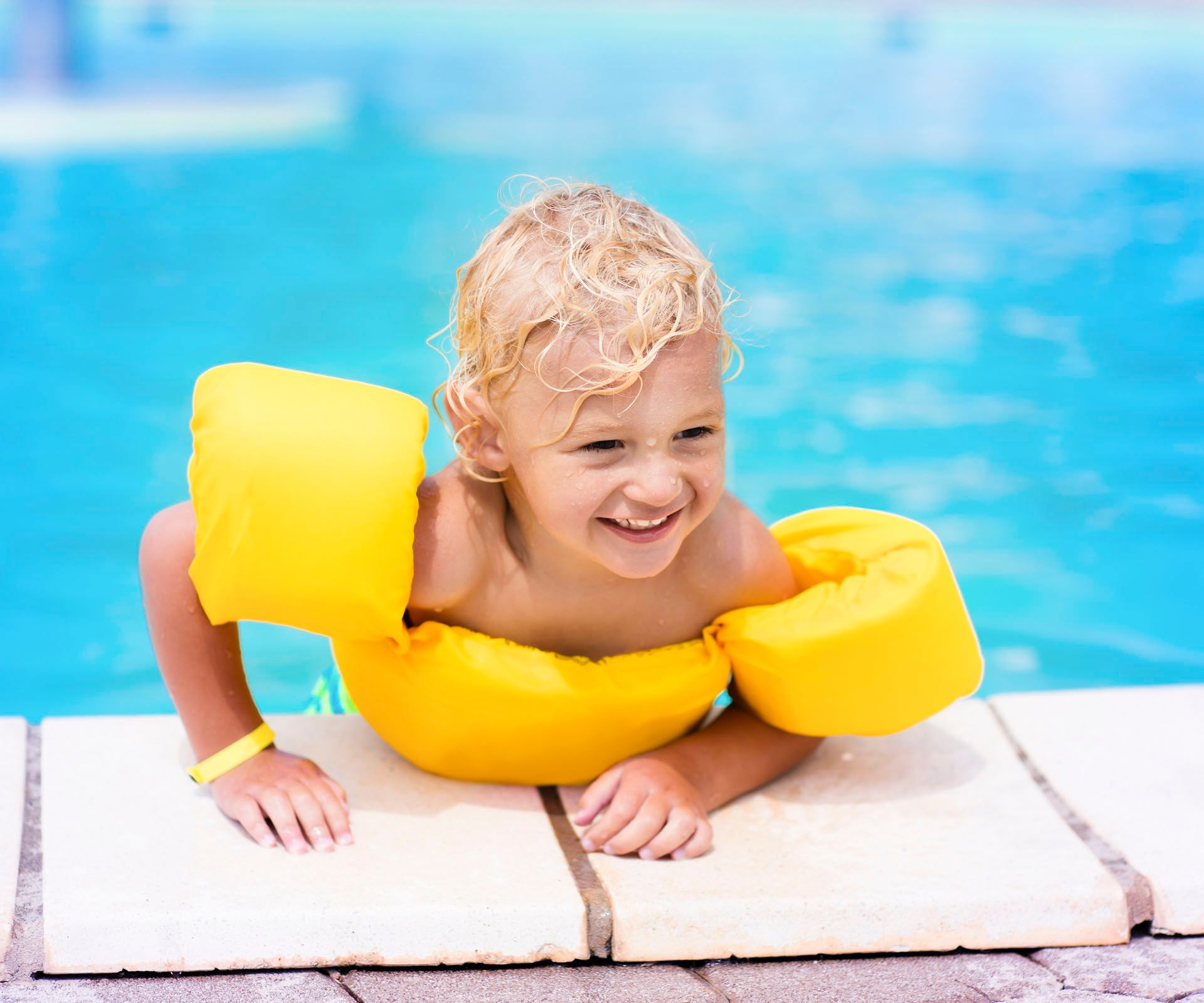 Kind mit Schwimmflügeln am Schwimmbecken