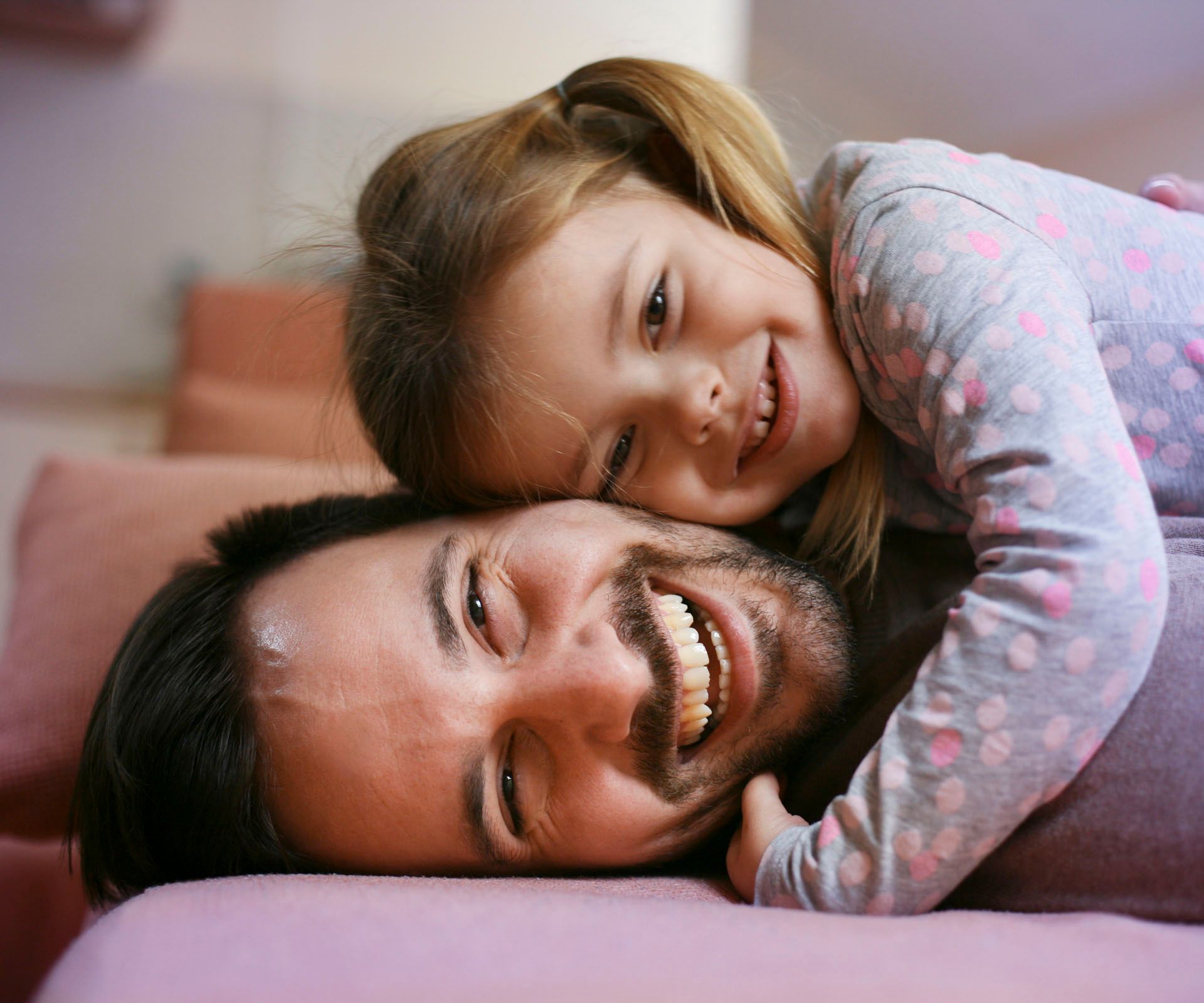 Vater und Tochter lachend auf Couch