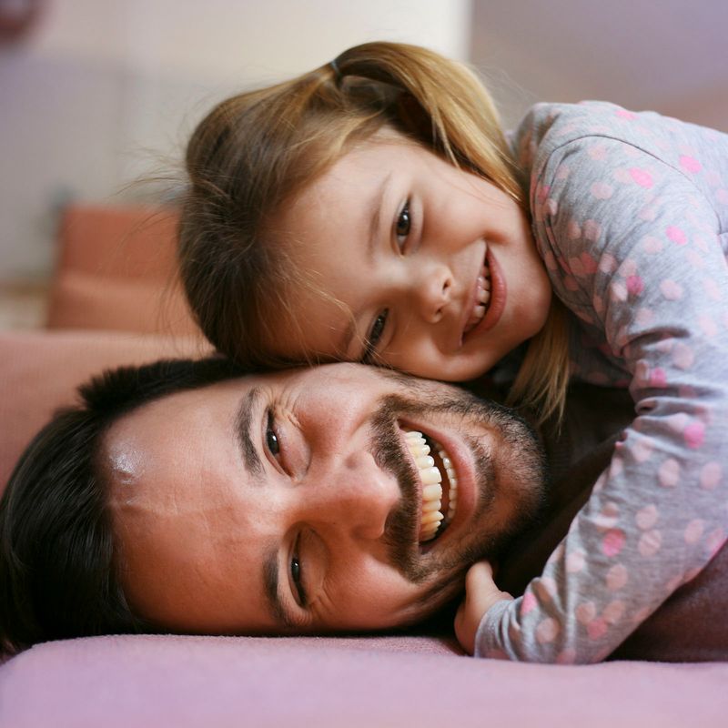 Vater und Tochter lachend auf Couch