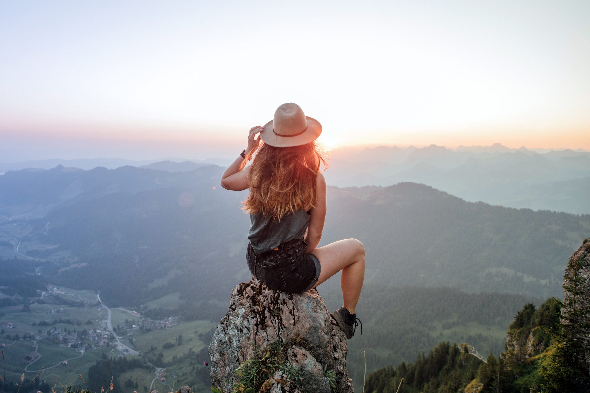 Frau auf Berggipfel genießt den Ausblick