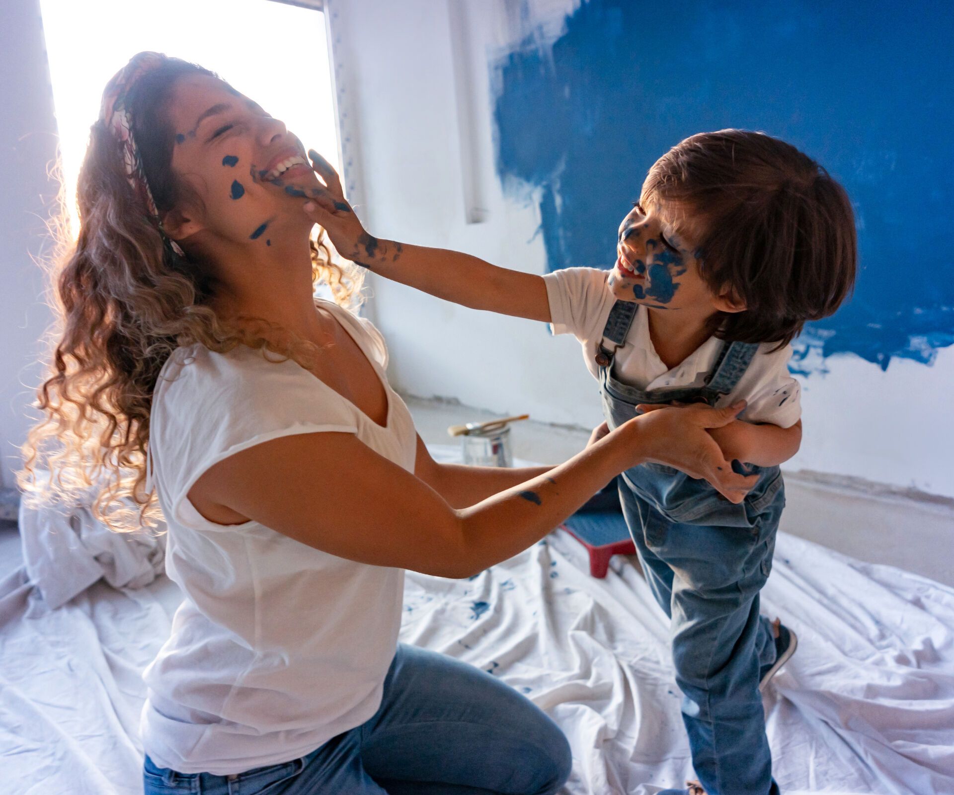 Mutter und Sohn machen Quatsch beim Streichen