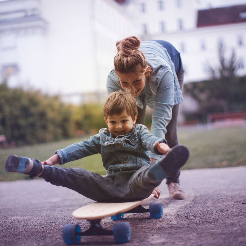 Sohn und Mutter spielen mit Skateboard