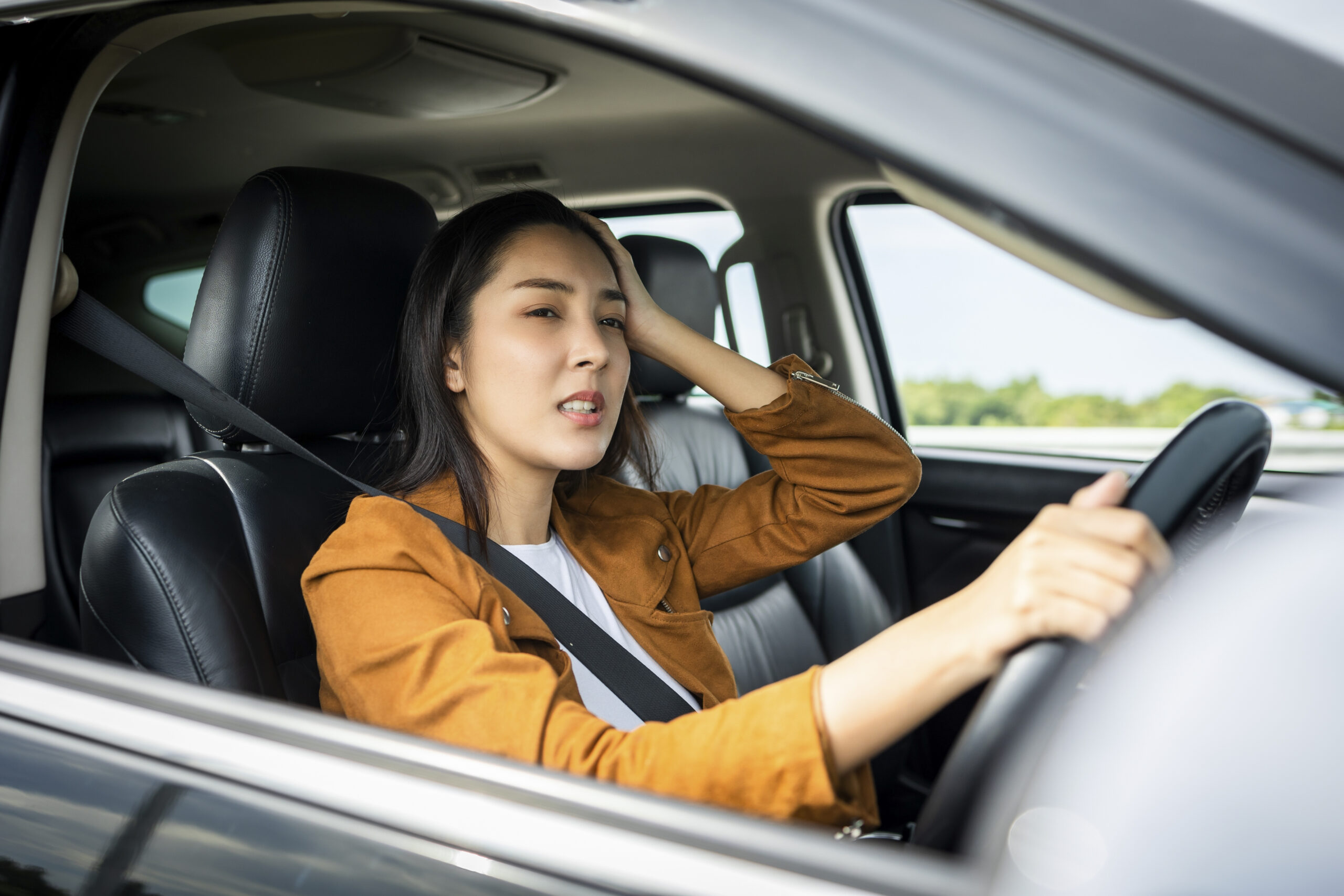 Frau greift sich an den Kopf im Auto