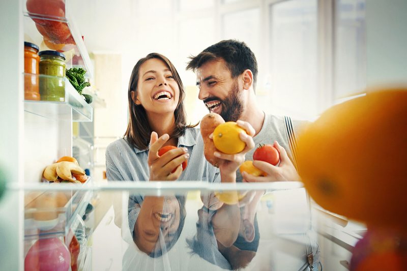 Paar holt sich Obst und Gemüse aus Kühlschrank