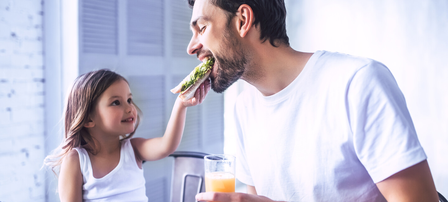 Kind füttert Mann mit Sandwich