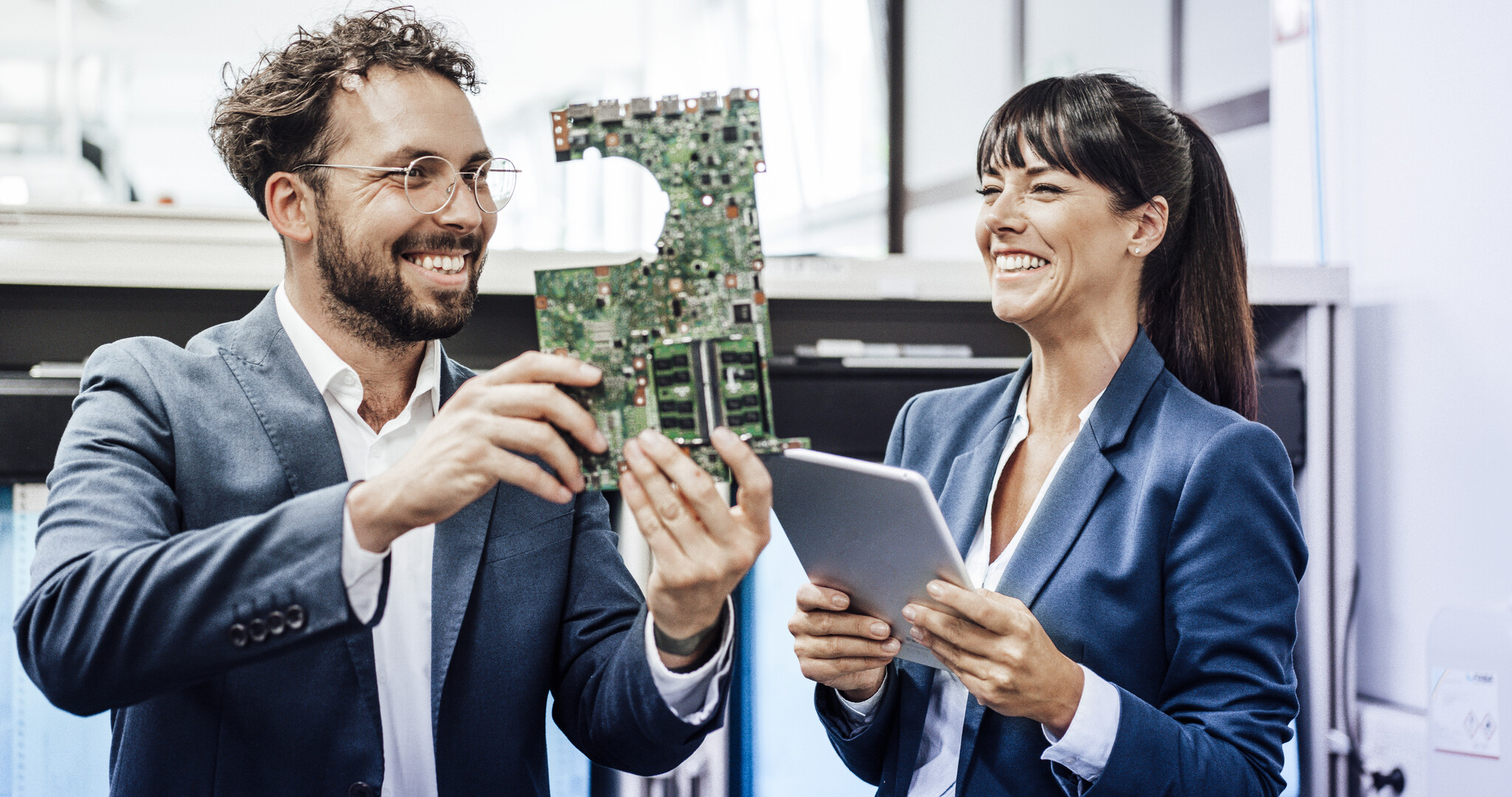 Frau und Mann halten lachend Platine und Tablet in die Kamera