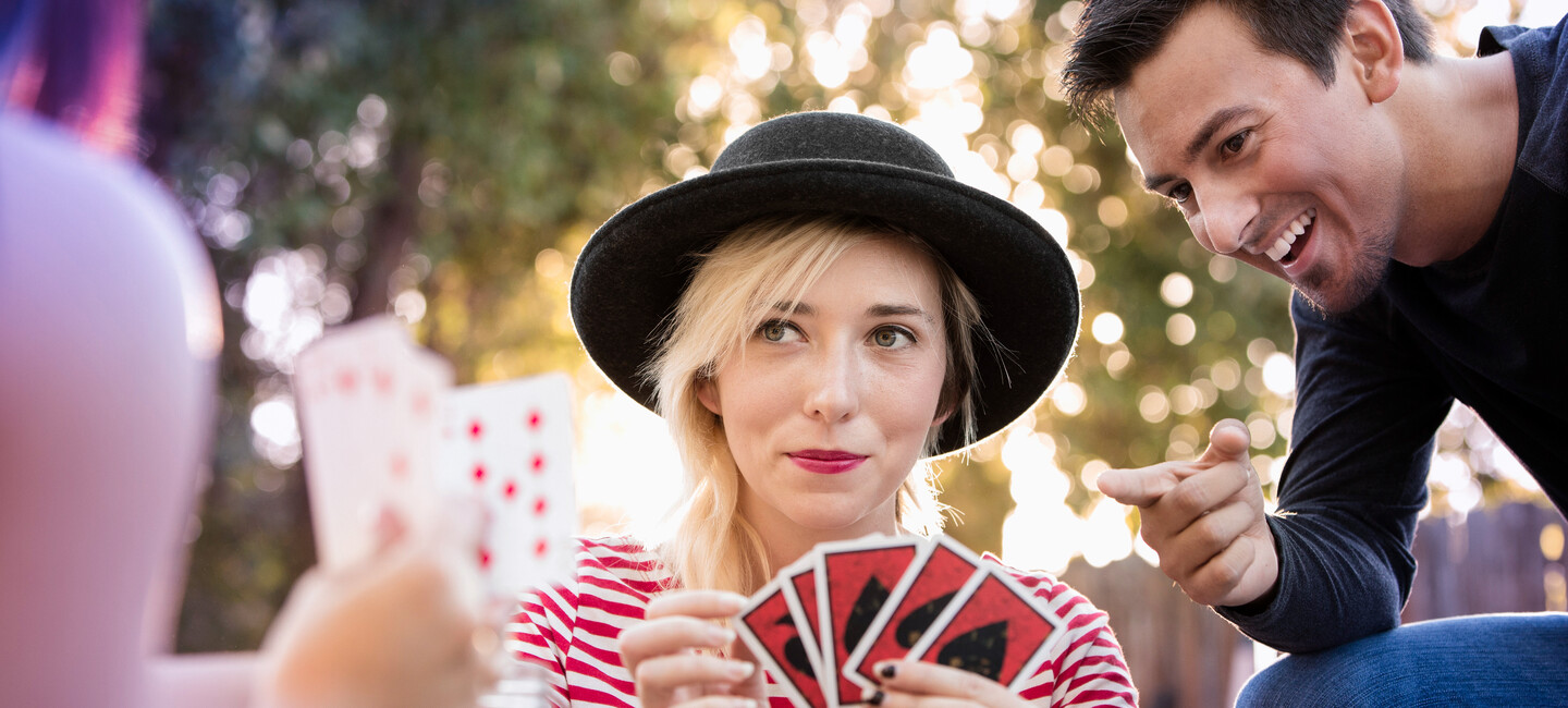 Frau mit Hut spielt Karten