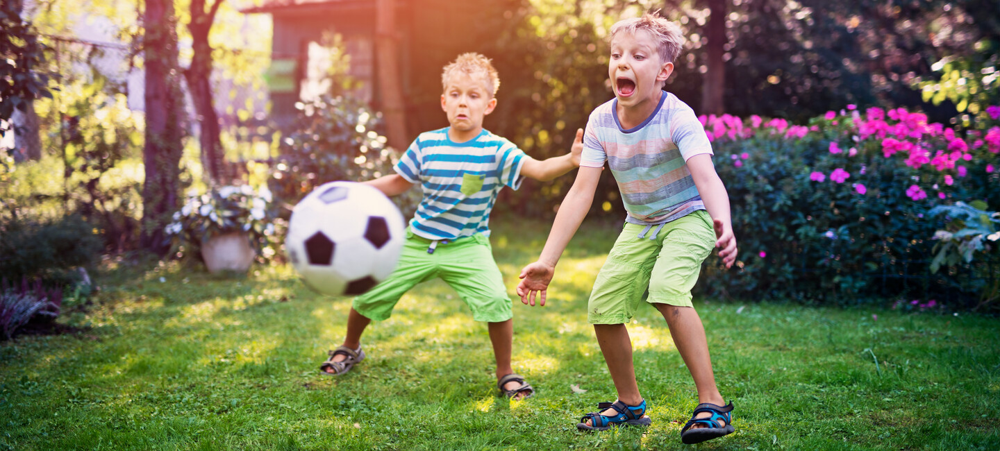 Jungs spielen Fußball im Garten