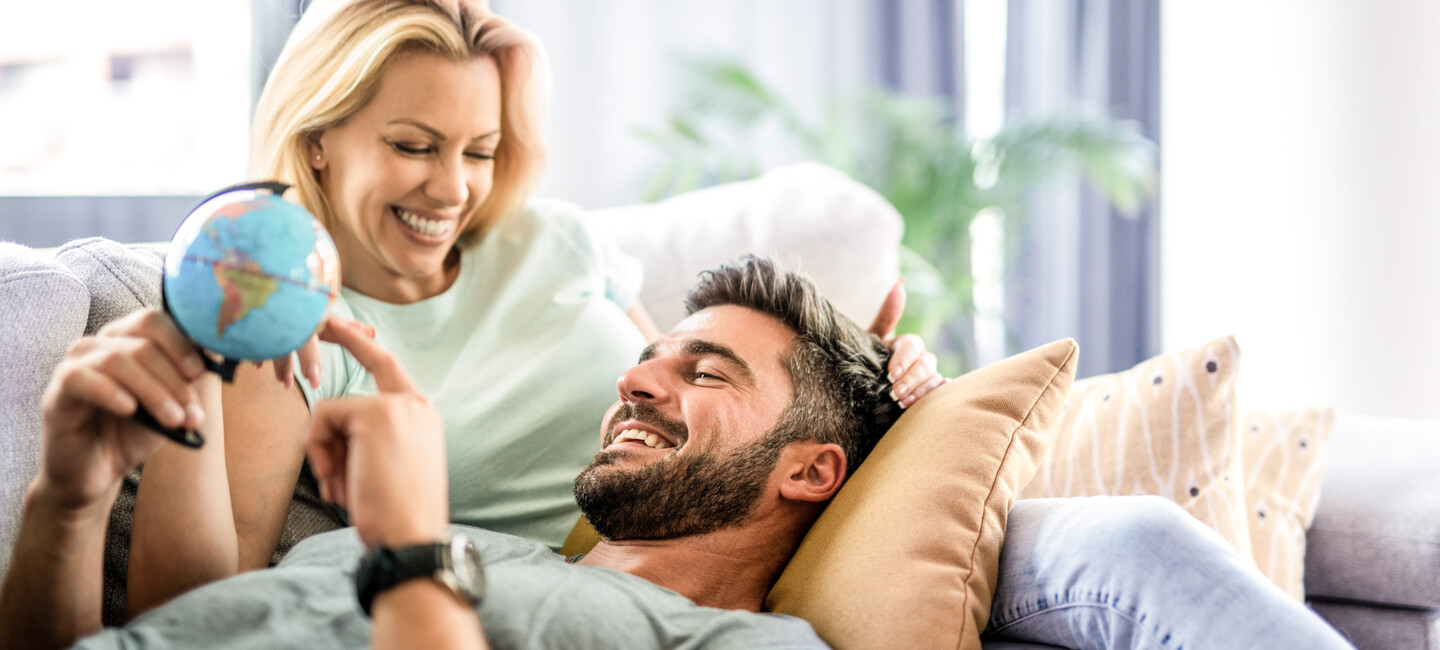 Mann und Frau liegen mit Globus auf der Couch