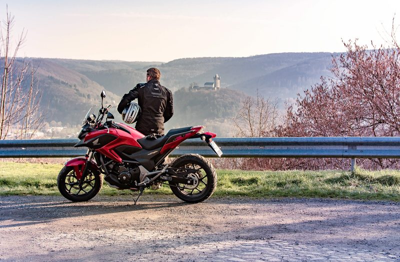 Mann mit Motorrad schaut in die Ferne