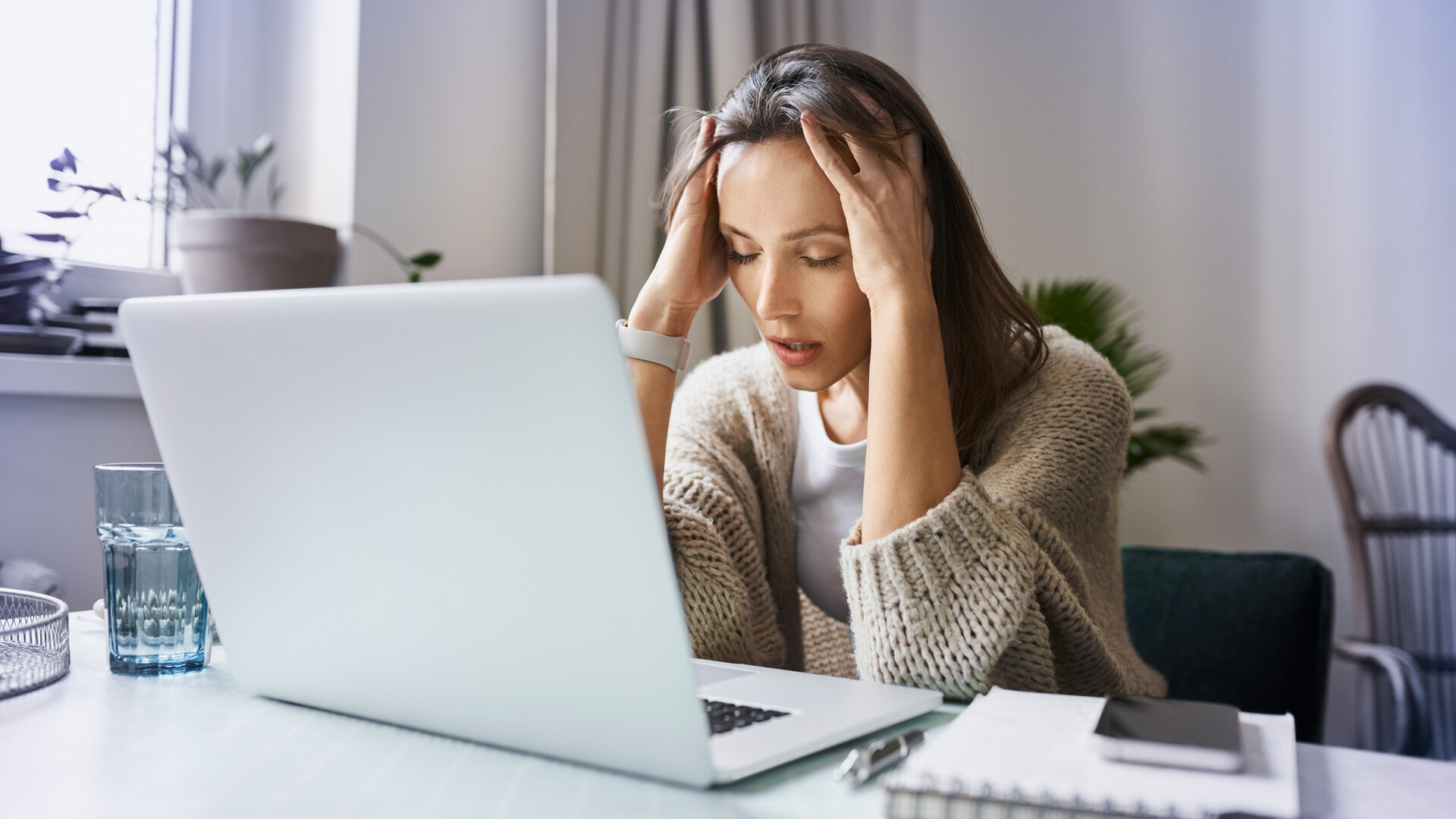 Frau sitzt vor Laptop und rauft sich die Haare