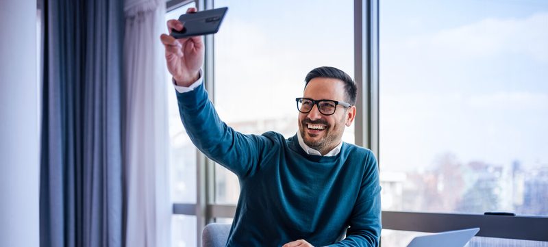 Mann mit Handy macht Selfie