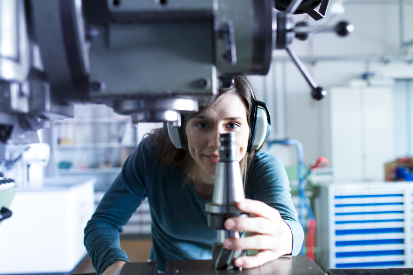 Frau mit Schutzbrille sitzt vor Fräßmaschine