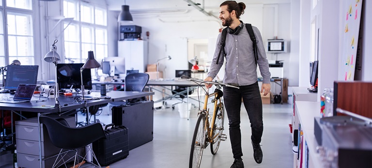 Mann steht mit Fahrrad in Büro