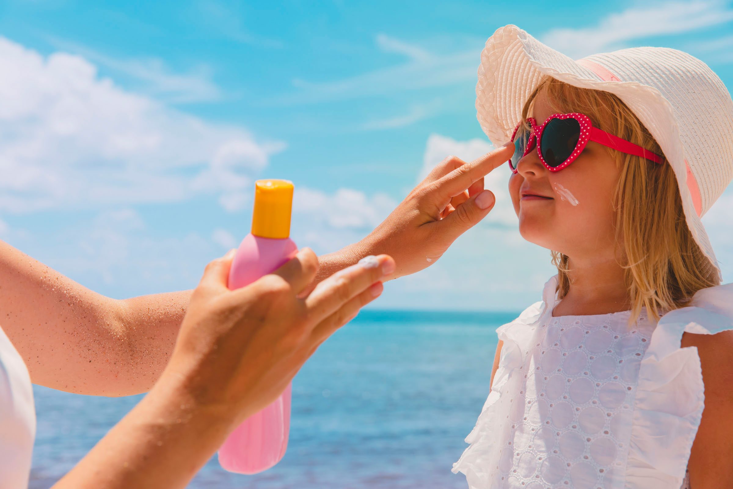 Kind wird mit Sonnencreme eingeschmiert
