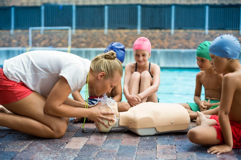 Schwimmlehrerin erklärt Kindern Beatmung