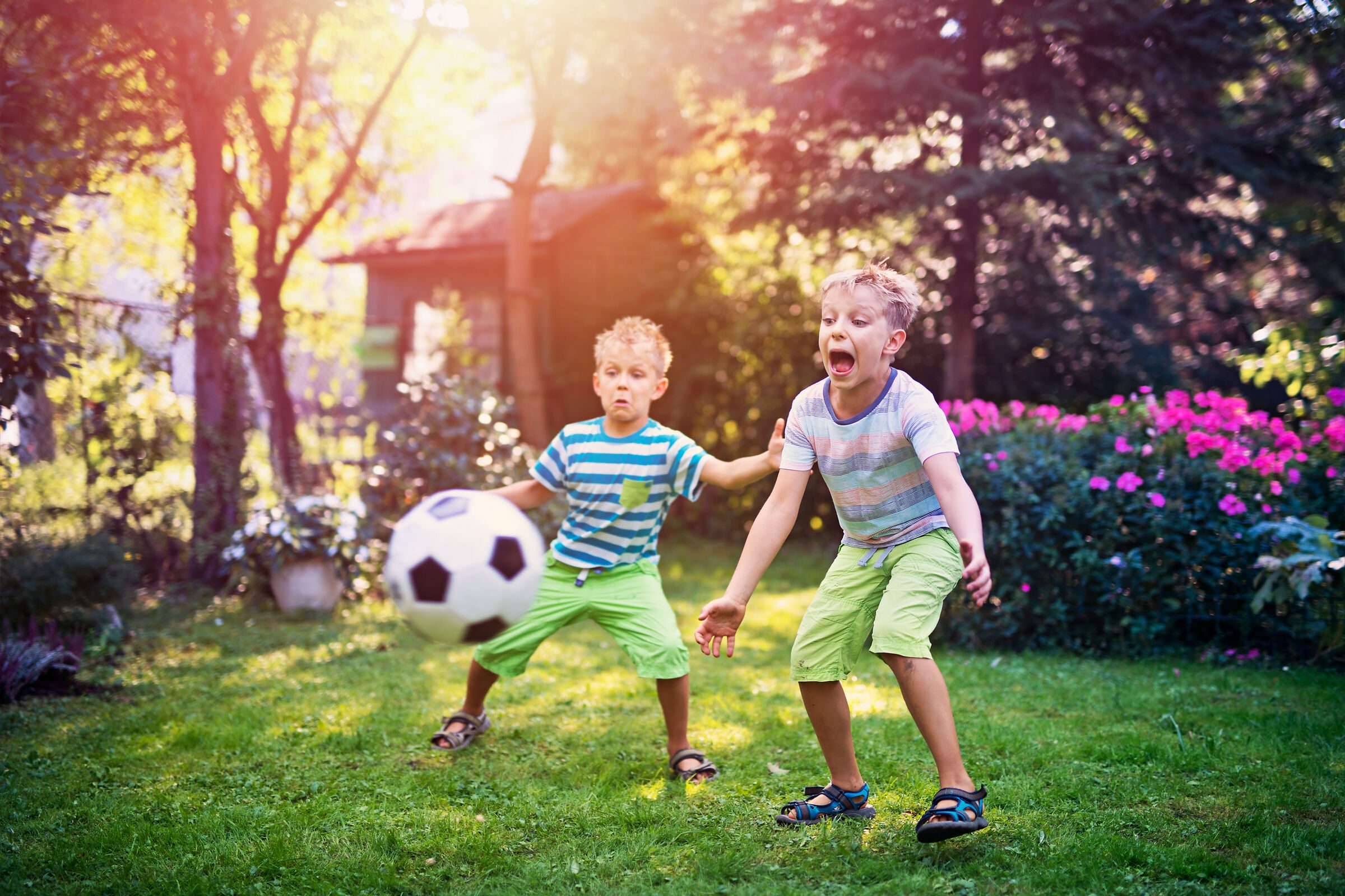 Zwei Kinder spielen Fußball im Garten